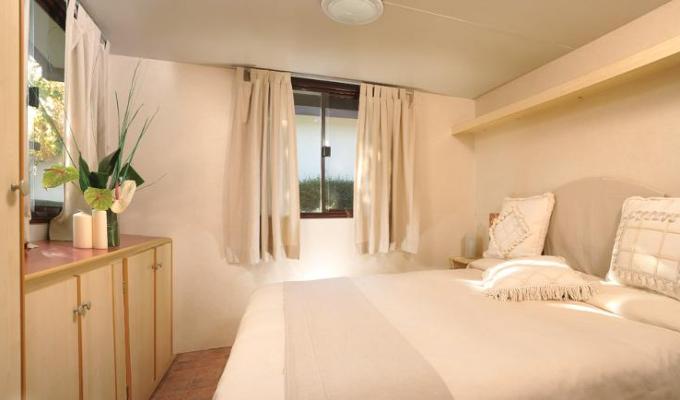 Camera da letto luminosa con letto matrimoniale e arredamento minimalista.