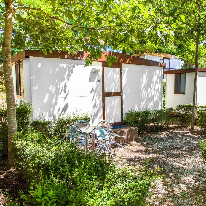 Small white cabins surrounded by greenery and outdoor seating.