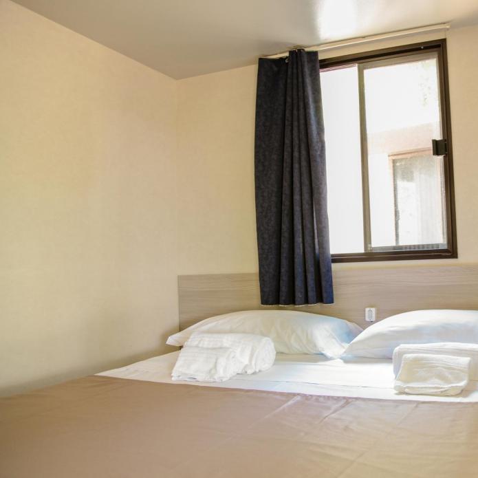 Simple bedroom with a window, double bed, and side table.