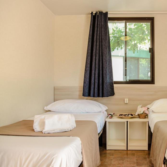 Room with three single beds, window, and central nightstand.