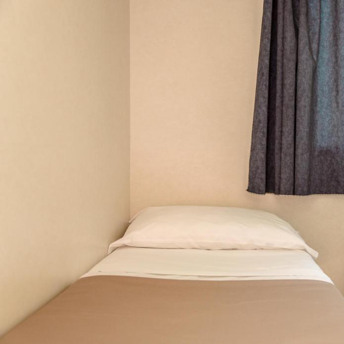 Small room with a single bed, window, and nightstand with a flower basket.