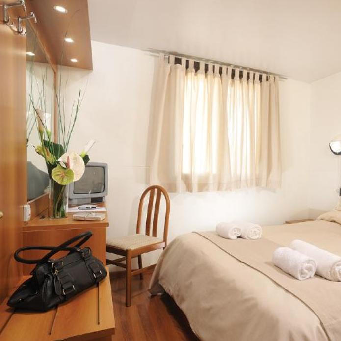 Cozy room with a double bed, TV, and desk, decorated in neutral tones.
