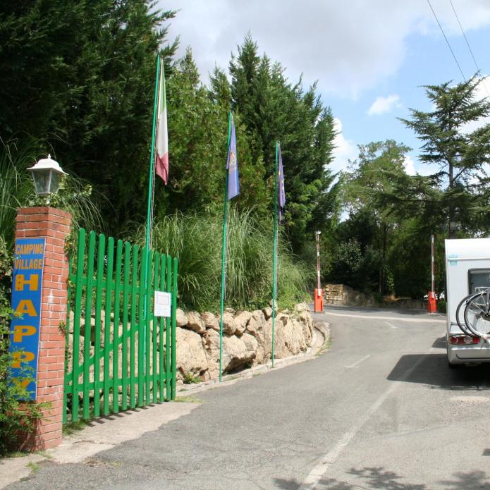 Eingang eines Campingplatzes mit geparktem Wohnmobil und Fahrrädern.